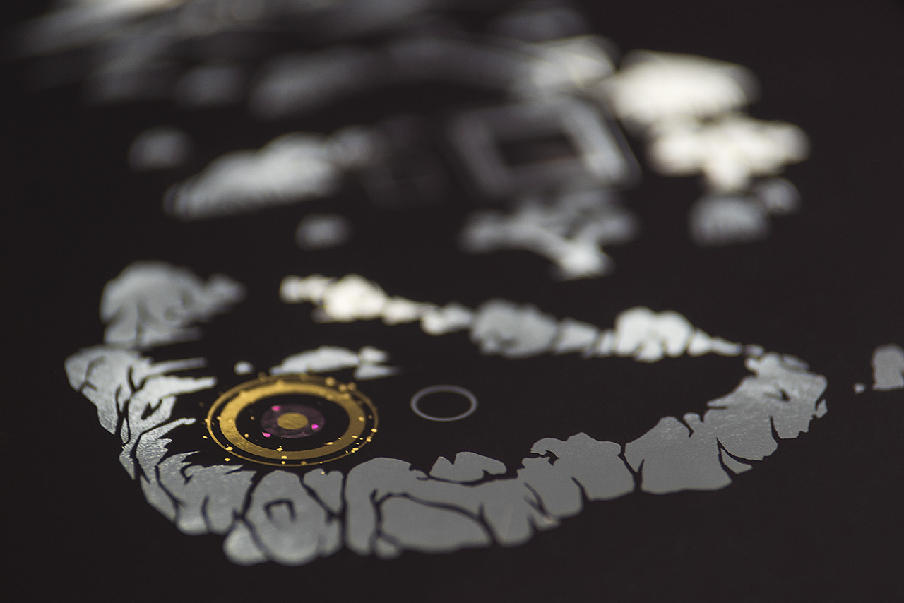 The camera's lense is focused on a golden sparkeling circle that is surrounded by silvery mountains – a scene from the mobile game SHI•RO. In the background, other silvery elements are blurred.