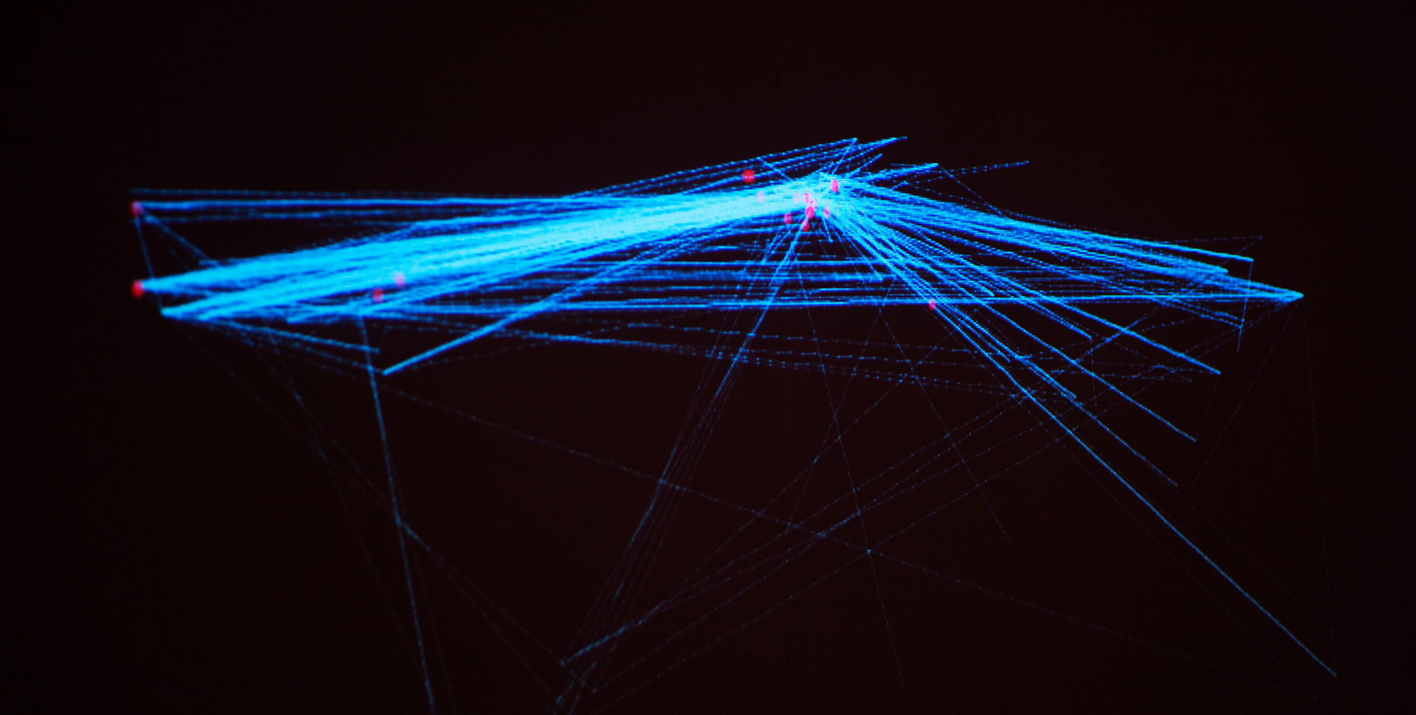 Photo of the installation: Blue lines connect pink dots on a projection.